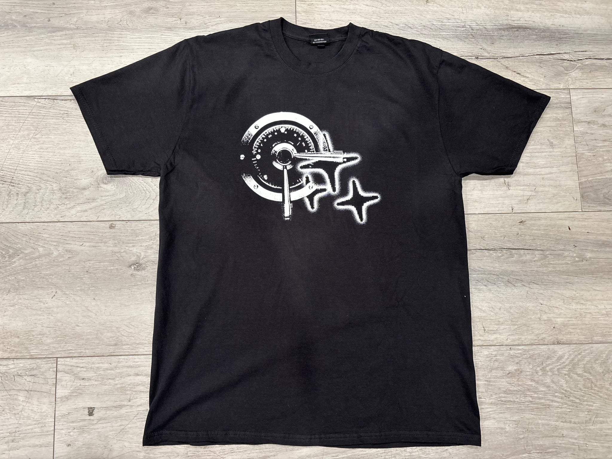 Black t-shirt with white graphic design on a wooden surface